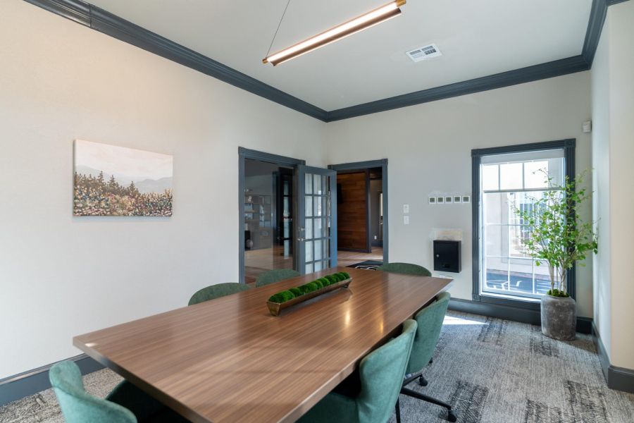 Attain on 5th apartment homes with Modern conference room with a wooden table, green chairs, large window, and wall art.