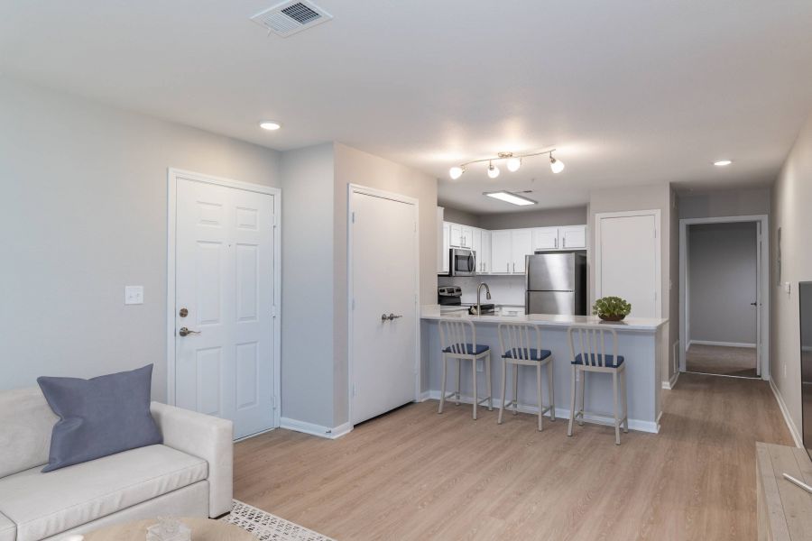 Attain on 5th apartment homes with Modern apartment with open kitchen, breakfast bar, and light wood floors; white walls and cabinets.