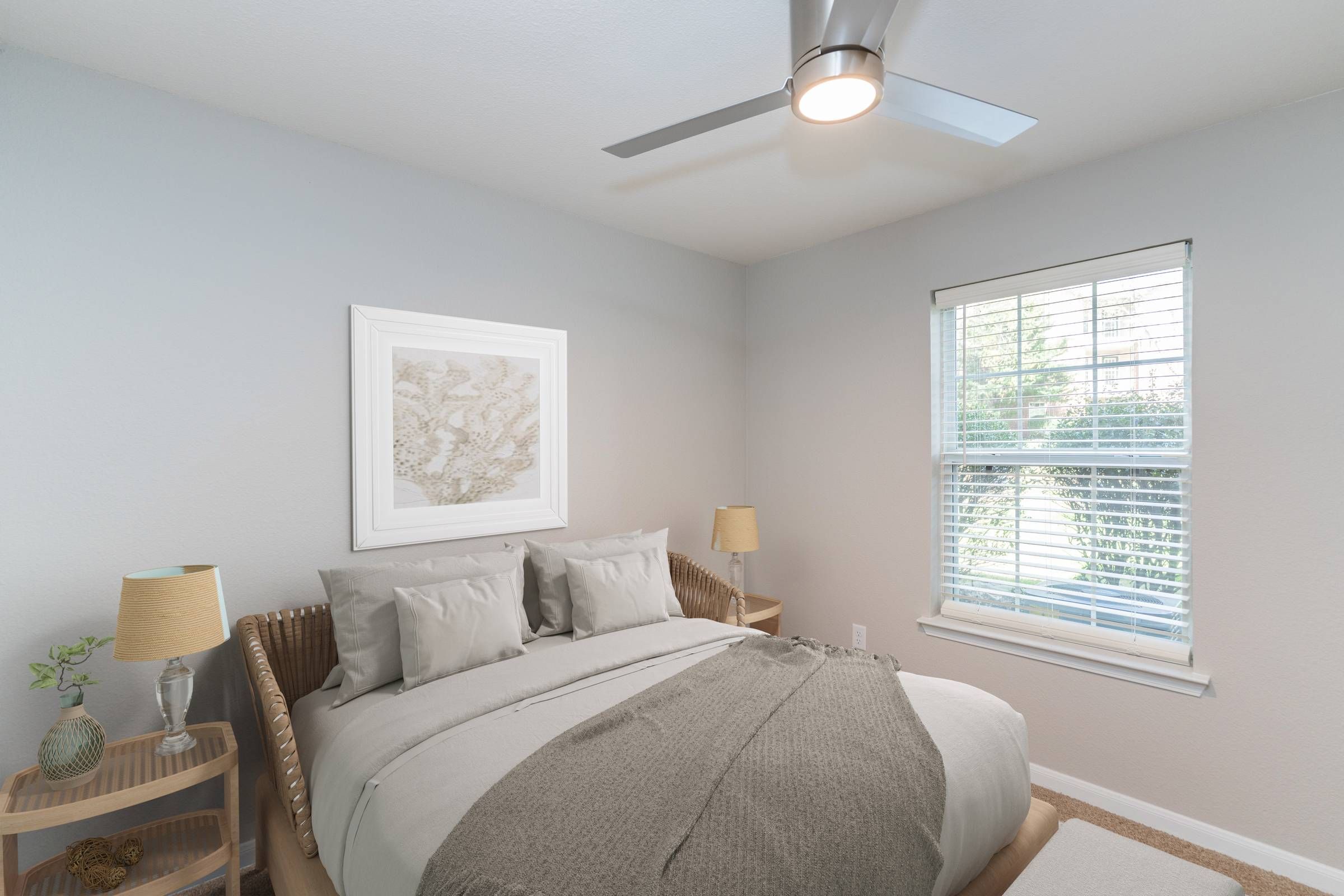Attain on 5th apartment homes with A cozy bedroom with a made bed, two lamps, a window, and a ceiling fan.