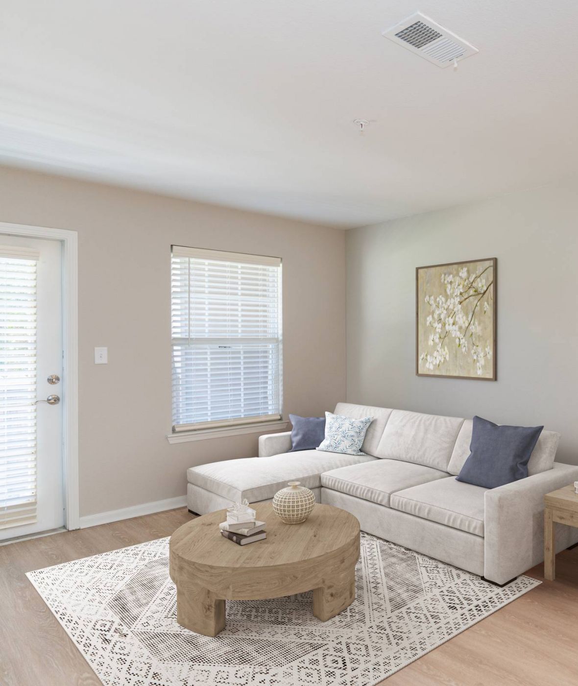 Attain on 5th apartment homes with Bright living room with a white sofa, round wooden coffee table, and light decor near a white front door.