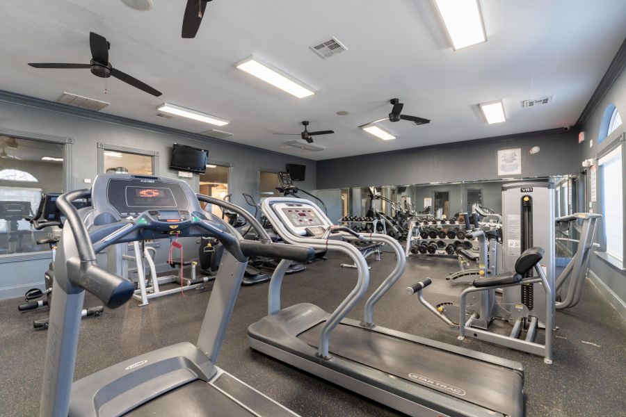 Attain on 5th apartment homes with A gym with treadmills, weight machines, free weights, mirrors, and TVs on the walls.
