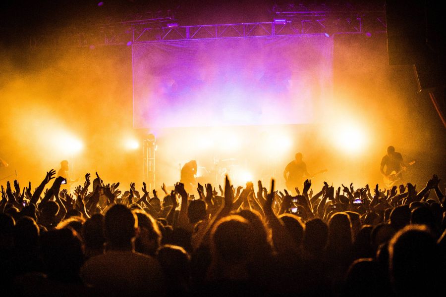 Attain on 5th apartment homes with Crowd cheering at a concert with bright stage lights and band silhouettes in the background.