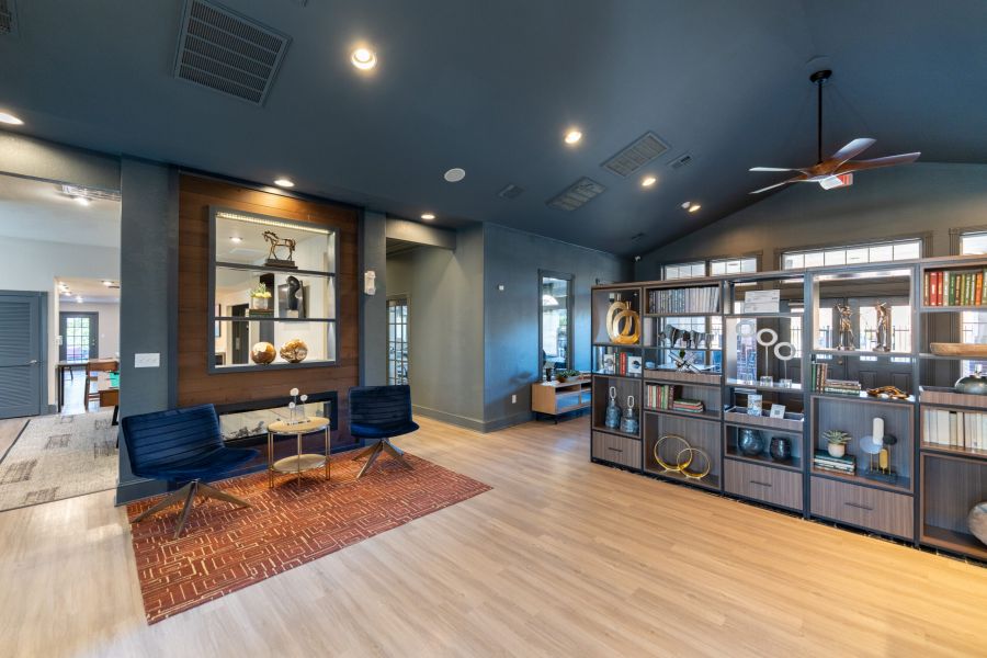 Attain on 5th apartment homes with Modern game room with a red pool table, built-in shelves, fireplace, and a view into a gym with exercise equipment.