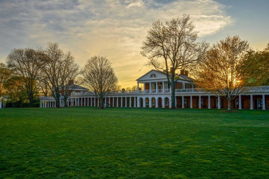 Attain on 5th apartment homes with Historic university building with columns and trees at sunset, viewed across a large grassy lawn.