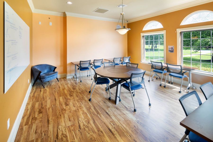 Attain on 5th apartment homes with A bright classroom with orange walls, wood floors, tables, chairs, and large windows letting in sunlight.