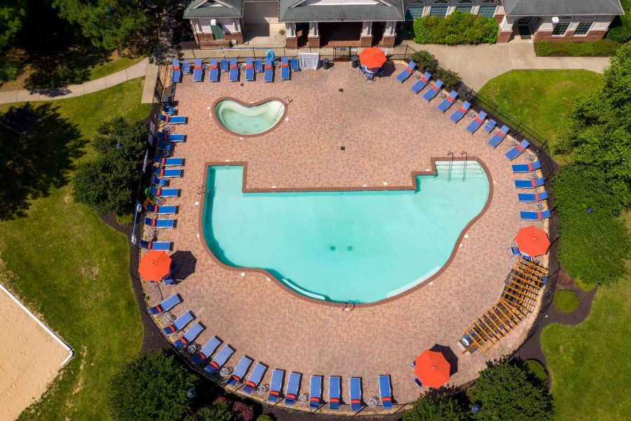 Attain on 5th apartment homes with Aerial view of a pool with lounge chairs and red umbrellas arranged around it, next to a small kiddie pool.